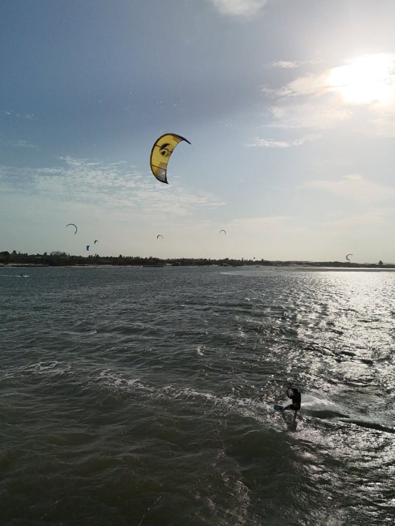 Kitesurf em Atins com pipa amarela e brilho no mar sob o sol