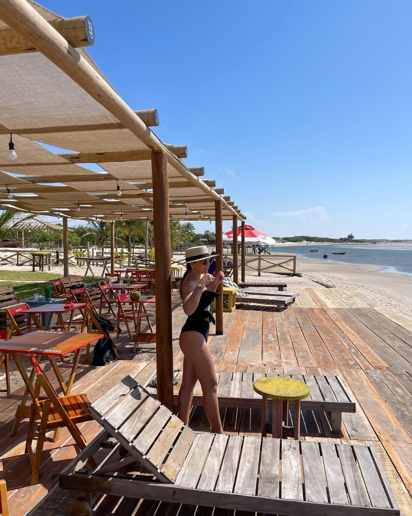 Visitante no deck de madeira de beach club com vista para praia e água em Atins