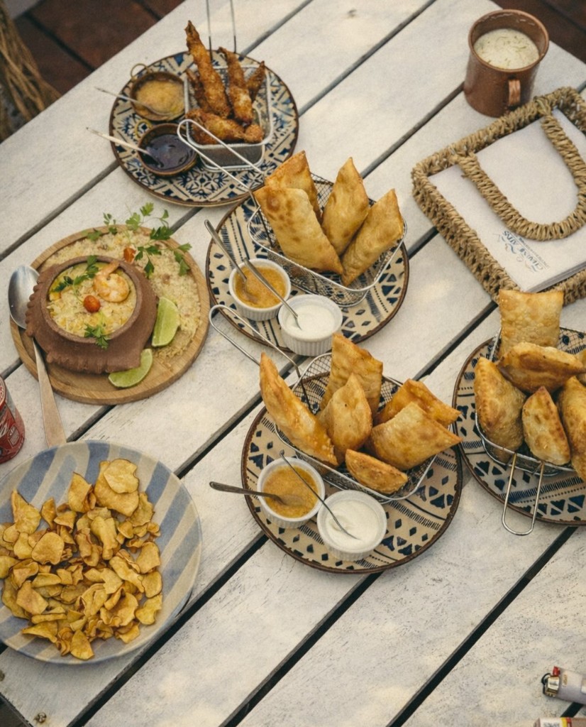 Petiscos, pastéis e pratos na mesa branca no Charm Atins
