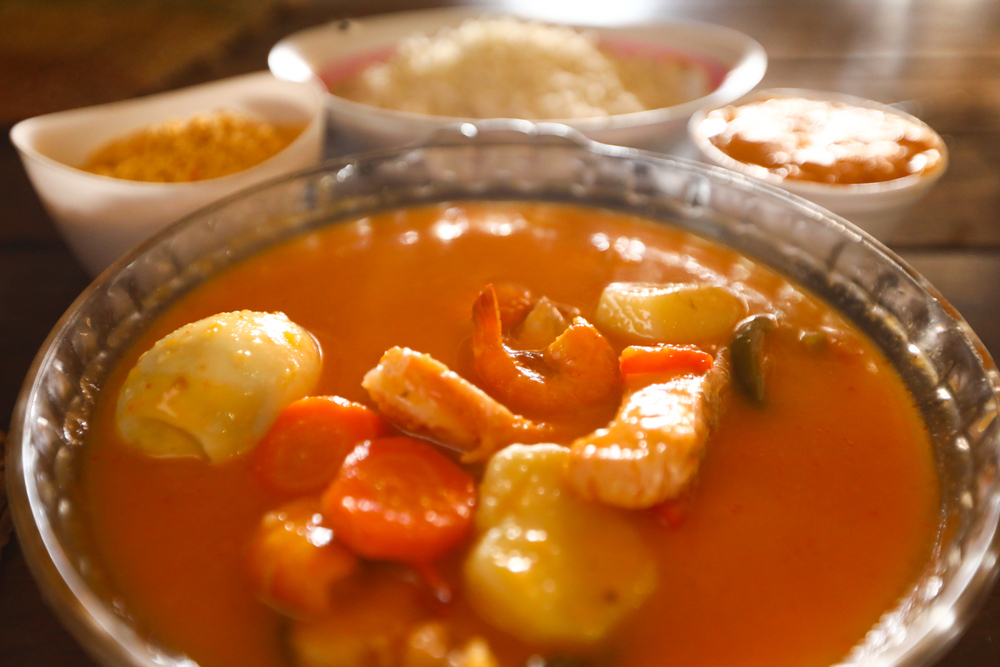 Mesa com moqueca, peixe grelhado e acompanhamentos em restaurante local