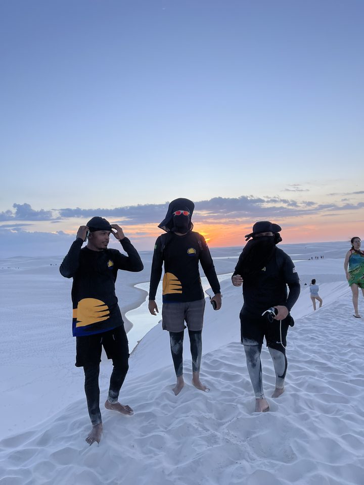 Guias fardados da Amo Lençóis nas dunas ao pôr do sol