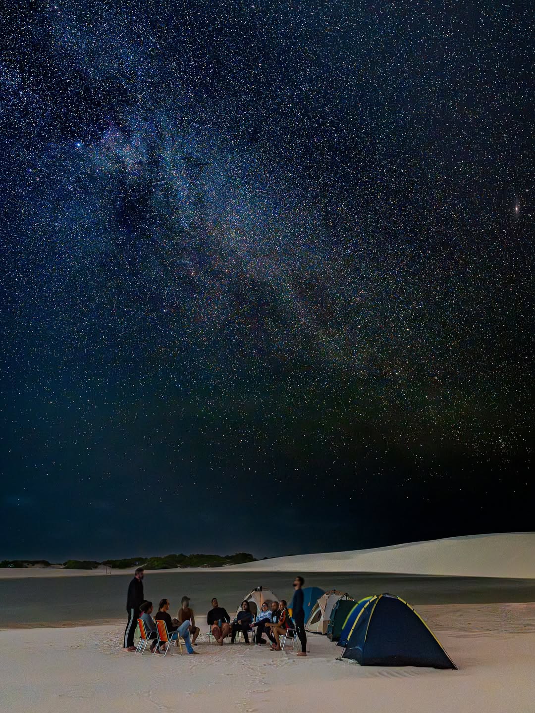 Grupo em acampamento nas dunas sob a via láctea durante a noite