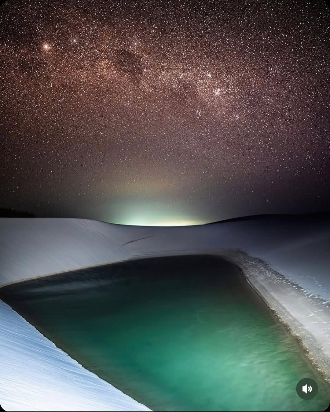 Lagoa entre dunas iluminada sob o céu noturno